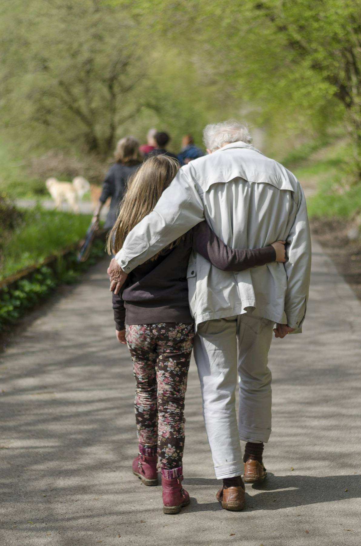 An older couple walking together along a tree-lined path